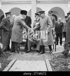 Winston Churchill saluta Joseph Stalin con il presidente Roosevelt al di fuori del palazzo di Livadia durante la conferenza di Yalta, febbraio 1945. Winston Churchill (in piedi a sinistra) scuote la mano con Joseph Stalin (in piedi a destra) al di fuori del palazzo di Livadia durante la conferenza di Yalta. Il presidente Roosevelt è seduto tra loro. Appena visibile tra Churchill e Stalin è ammiraglio William D Leahy, Capo del personale di Roosevelt. Foto Stock