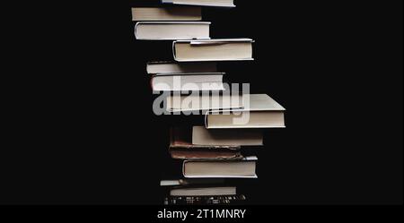 Composizione di libri accumulati su sfondo nero. Composizione centrale minima. Copia spazio. Concetto educativo Foto Stock