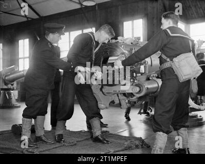 La Royal Navy durante la Seconda Guerra Mondiale e in HMS RALEIGH, naval training base a Torpoint, Cornovaglia nuove reclute per la marina militare il caricamento del proiettile nella culatta di 6 pollici di pistola. La pistola è in ambienti chiusi in una camera grande. Questa foto è stata scattata da una serie di immagini in seguito al progresso di un uomo (John Smith) congiungente la Royal Navy e passando attraverso la formazione. John Smith è stata apparentemente grati per l'allenamento fisico che ha reso il sollevamento dei gusci pesante possibile per lui. Foto Stock