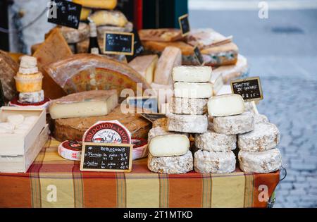 Bancarelle di formaggi locali artigianali in un mercato all'aperto di Annecy, Francia, con un'ampia selezione di formaggi duri e morbidi Foto Stock