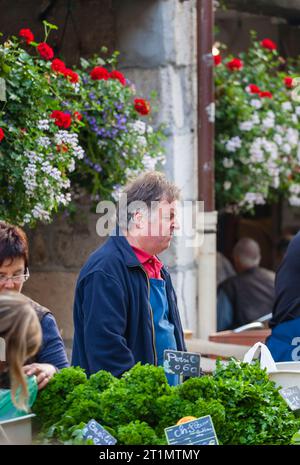 Uno stallholder francese del posto tende le sue verdure fresche e i suoi prodotti al mercato alimentare all'aperto nella città vecchia di Annecy, in Francia Foto Stock