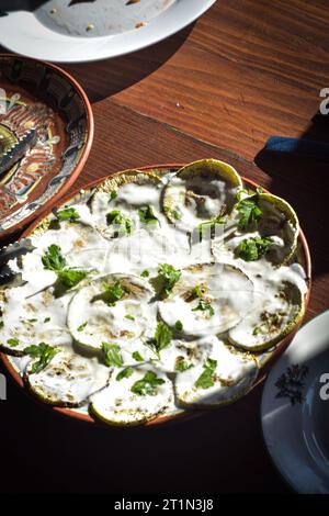 Zucchine al forno con yogurt e prezzemolo su un tavolo di legno, Macedonia Foto Stock