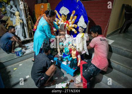 Nuova Delhi, India. 14 ottobre 2023. Gli artisti sono visti osservare l'adornamento dell'idolo di argilla della dea Durga in preparazione del prossimo festival Durga Puja al tempio Sarojini Nagar Kalibari. Durga Puja è un festival indù celebrato principalmente nel Bengala Occidentale e dalle comunità bengalesi di tutto il mondo. Si tratta di una celebrazione di più giorni dedicata alla dea Durga, che simboleggia il potere femminile divino e la vittoria del bene sul male. (Foto di Pradeep Gaur/SOPA Images/Sipa USA) credito: SIPA USA/Alamy Live News Foto Stock