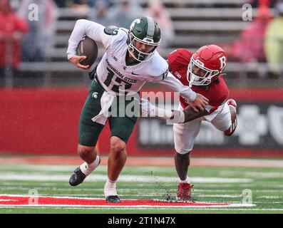 Piscataway, New Jersey, USA. 14 ottobre 2023. Il quarterback dei Michigan State Spartans Katin Houser (12) fu abbattuto dal defensive back dei Rutgers Scarlet Knights Desmond Igbinosun (4) durante la partita di football NCAA tra i Michigan State Spartans e i Rutgers Scarlet Knights allo SHI Stadium di Piscataway, New Jersey Mike Langish/CSM/Alamy Live News Foto Stock