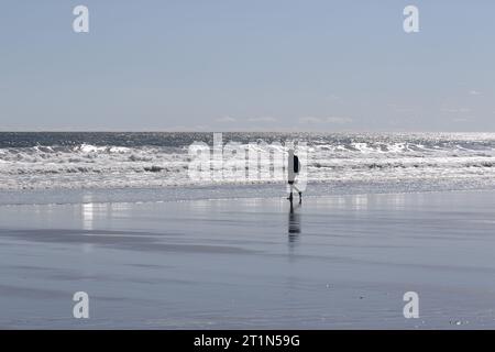 Un uomo in silhouette che cammina su Good Harbor Beach a Gloucester, Massachusetts Foto Stock
