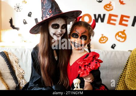 Bambine vestite per Halloween che abbracciano a casa Foto Stock