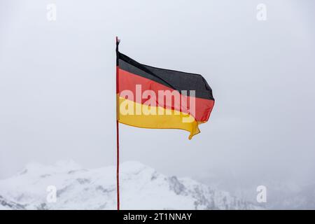 Bandiera nazionale della Germania contro le montagne invernali Foto Stock