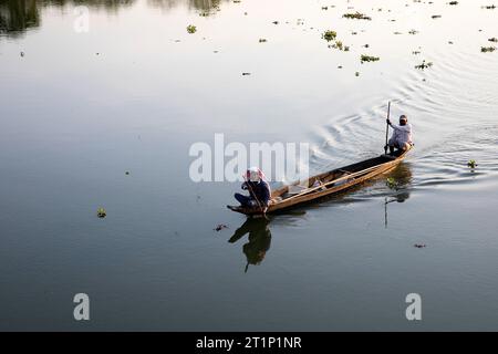 Pescatori locali in una tradizionale barca da pesca in legno su un fiume sull'isola Majuli in assam, tornando a casa prima del tramonto, in india Foto Stock