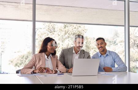 Tre dipendenti aziendali che utilizzano un computer portatile che lavorano in ufficio durante una riunione. Foto Stock