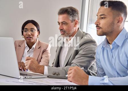 Team di dirigenti internazionali che analizzano i dati del digital banking su un laptop. Foto Stock