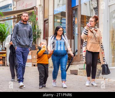 Donna incinta che cammina con la famiglia in una tranquilla strada cittadina - Loches, Indre-et-Loire (37), Francia. Foto Stock