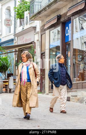 Coppia matura che guarda le vetrine dei negozi sul lato opposto della strada stretta - Loches, Indre-et-Loire (37), Francia. Foto Stock