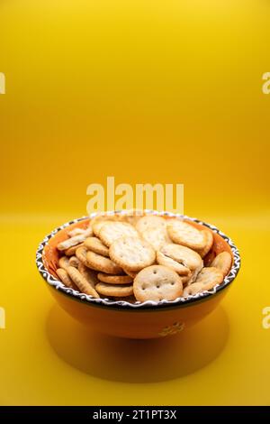 Vista dall'alto di una ciotola di cracker su sfondo giallo Foto Stock