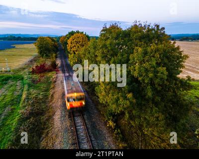Riprese con droni di una ferrovia in un ambiente autunnale con un treno in movimento, Ungheria Foto Stock