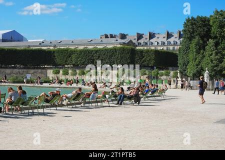 Persone sedute su sedie sparse per Bassin Octogonal, nel giardino delle Tuileries godendosi il sole, un'attività gratuita nel parco pubblico di Parigi, in Francia Foto Stock