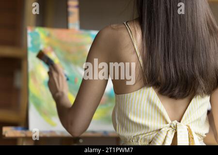 Vista posteriore di una giovane pittrice che dipinge su tela Foto Stock