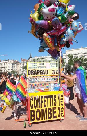 Un fornitore con un palo di palloncini novità in vendita a una marcia di ORGOGLIO e festa in PL. Bellecour, in una giornata di sole a Lione, in Francia Foto Stock