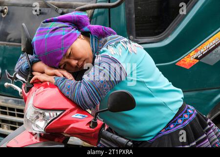 BAC ha, Vietnam. Giovane donna al mercato che riposa sulla motocicletta. Provincia di Lao Cai. Foto Stock