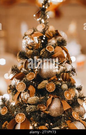 Albero di Natale natalizio decorato con arance secche, coni di pino e mandarini. Dettagli accoglienti. Stagione invernale alla vigilia delle vacanze. Cartolina verticale Foto Stock