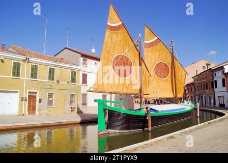 La Comacina è una storica imbarcazione a vela tipica della città di Comacchio, Emilia Romagna, Italia. La terza vela, così chiamata perché il punto in cui l'antenna è fissata all'albero è di circa un terzo della sua lunghezza, è tipica delle imbarcazioni del Mare Adriatico. Questo tipo di vela rappresenta la transizione più naturale dalle più antiche vele quadrate in latteo alle vele assiali tipiche delle moderne barche a vela. Le più antiche testimonianze relative all'uso di questo tipo di vela risalgono al XVII secolo. Foto Stock