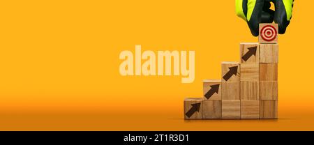 Guanti disposti a mano con blocchi di legno come gradini con un simbolo di destinazione sull'ultimo gradino e frecce marroni rivolte verso l'alto. Concetto di scala di successo. Foto Stock