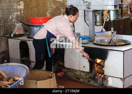 Utilizzo di marmellate di cocco per riscaldare la miscela di caramelle di cocco in una fabbrica di caramelle di cocco di Mekong River, Vietnam. Foto Stock