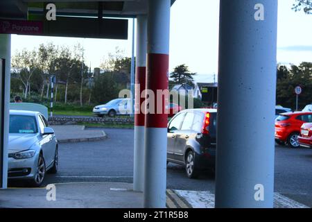 Una foto di colonne bianche che reggono un edificio con un parcheggio sullo sfondo. Foto Stock
