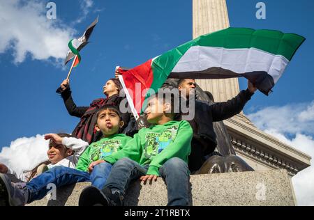 Londra, Regno Unito. 14 ottobre 2023: I genitori musulmani sventolano bandiere con i loro tre figli piccoli alla base della colonna di Nelson a sostegno della Palestina e contro Foto Stock