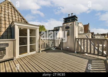 un'area esterna con pavimento in legno e finiture bianche sulle pareti, le finestre e le porte aperte Foto Stock