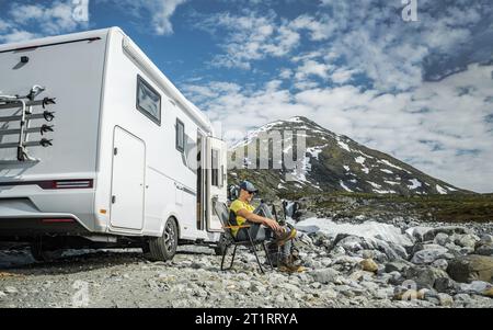 Camper caucasico viaggiante turista che si prepara per un'escursione di fronte al suo camper Van da qualche parte nella natura selvaggia Foto Stock