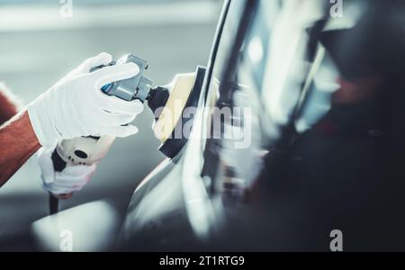 Detailer professionale lavoratore automobilistico che lucida il corpo del veicolo dopo la ceretta in primo piano foto Foto Stock