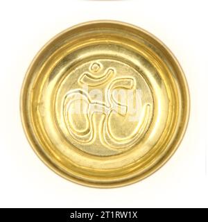 una tradizionale ciotola di preghiera dorata con un antico simbolo indù om scolpito all'interno del piatto isolato su uno sfondo bianco Foto Stock