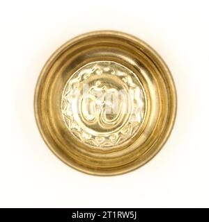 una tradizionale ciotola di preghiera dorata con un antico simbolo indù om scolpito all'interno del piatto isolato su uno sfondo bianco Foto Stock