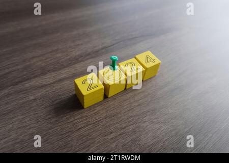 Primo piano di un perno verde sulla parte superiore dei blocchi gialli con il numero 2024. Concetto di obiettivi e risoluzioni per l'anno nuovo Foto Stock