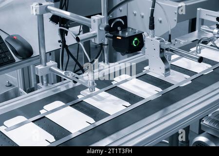 Gli elementi delle scatole corton vengono raccolti in pila. Linea di trasporto per la produzione di scatole. La macchina taglia scatole di cartone da fogli di cartone. Int Foto Stock