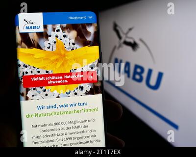 Persona che possiede un telefono cellulare con pagina web dell'associazione Naturschutzbund Deutschland e.V. (NABU) con logo. Concentrarsi sul centro del display del telefono. Foto Stock