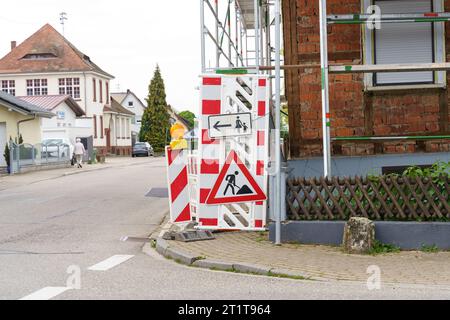 Sulla struttura racchiusa è presente un segnale di avvertenza per i lavori stradali e la direzione del movimento dei pedoni. Segnali stradali. Foto Stock