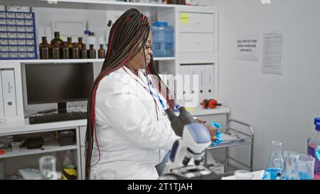 Scienziata afroamericana sicura di sé, con belle trecce, sorridendo mentre si tengono i guanti in laboratorio, immersa in una ricerca medica rivoluzionaria Foto Stock