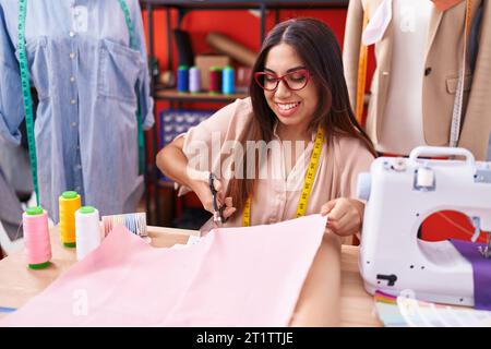 Giovane bella donna araba su misura sorridente sicuro di taglio panno presso atelier Foto Stock