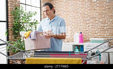 Uomo di mezza età che tiene cesto con i vestiti nella lavanderia Foto Stock