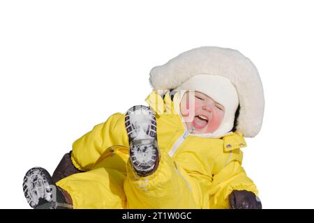 Il bambino più piccolo cavalca uno scivolo giocando su un parco giochi invernale, isolato su sfondo bianco. Un bambino con una tuta gialla su uno scivolo per bambini i Foto Stock