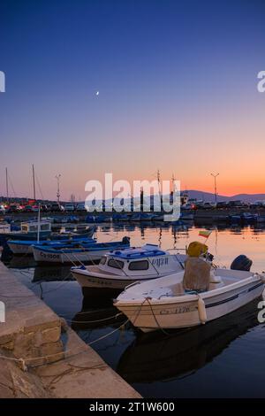 sozopol, bulgaria - 3 settembre 2019: piccole imbarcazioni da pesca nel porto al tramonto. cielo senza nuvole che si riflette nell'acqua Foto Stock