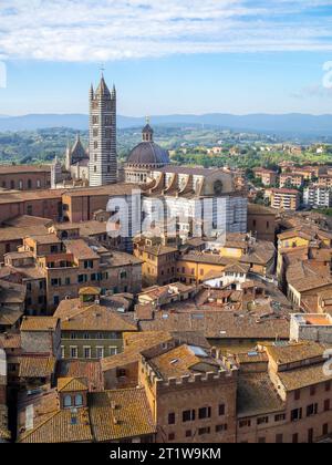 Il Duomo di Siena si vede sopra i tetti degli edifici con la campagna sullo sfondo Foto Stock