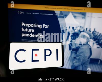 Persona in possesso di cellulare con logo della Coalition for Epidemic Preparedness Innovations (CEPI) davanti alla pagina web. Concentrarsi sul display del telefono. Foto Stock