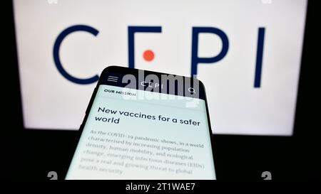 Telefono cellulare con sito web della Coalition for Epidemic Preparedness Innovations (CEPI) davanti al logo. Mettere a fuoco in alto a sinistra sul display del telefono. Foto Stock