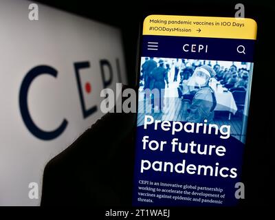 Persona in possesso di smartphone con pagina web della Coalition for Epidemic Preparedness Innovations (CEPI) con logo. Concentrarsi sul centro del display del telefono. Foto Stock