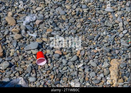 Vetro di plastica rosso di spazzatura lavato sulla spiaggia mediterranea 5 Foto Stock