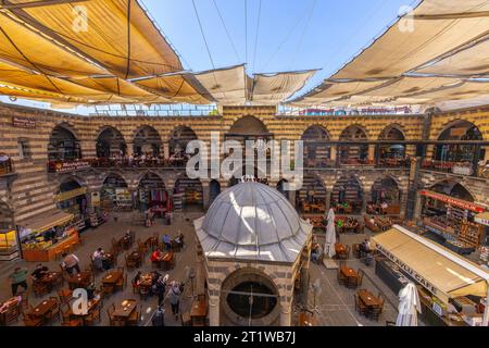 DIYARBAKIR, TURCHIA, 5 OTTOBRE 2023: Veduta di Hasanpasa Khan, edificio storico medievale dove la gente fa colazione e piccoli negozi, il centro Foto Stock