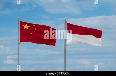 Indonesia e Cina bandiere che sventolano insieme sul cielo nuvoloso blu, concetto di due relazioni tra paesi Foto Stock