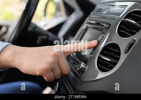 Scelta della radio preferita. Donna che preme il pulsante sull'audio del veicolo in auto, primo piano Foto Stock